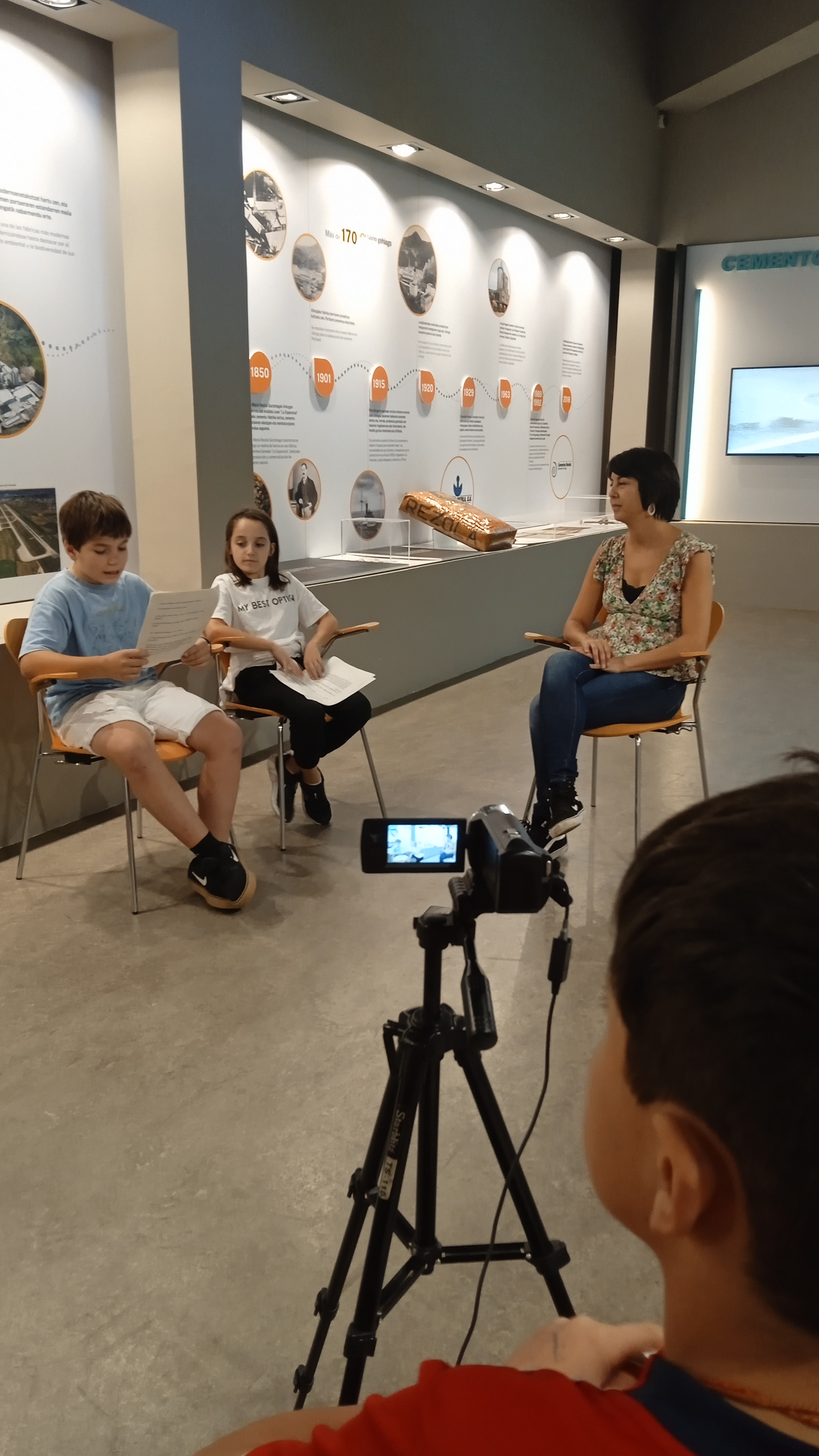 Imagen de una cámara de video y unos jóvenes sentados en una aula.