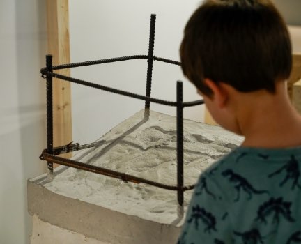 Un niño de espaldas con una pieza de cemento de la exposición del museo cemento rezola.